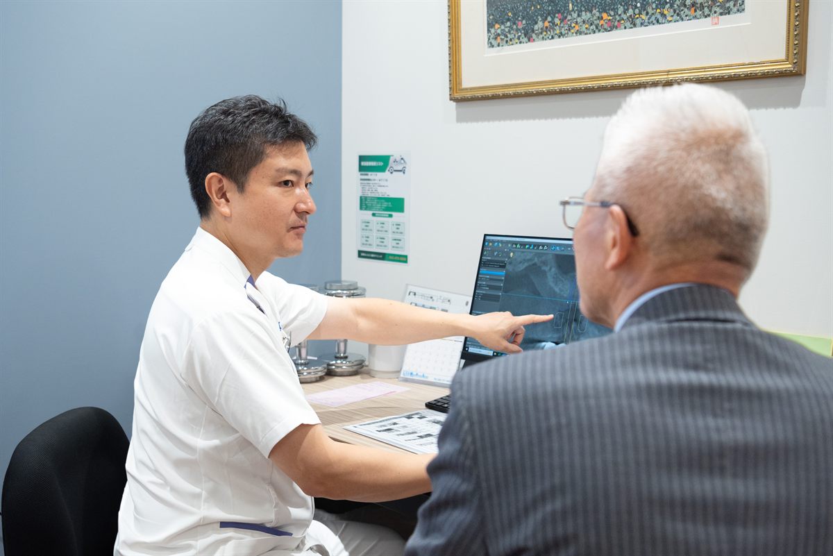 理事長が資料を示しながら患者様に説明している様子
